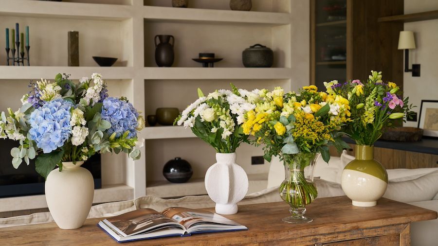 A blue hydrangea bouquet, a white bouquet, a yellow bouquet and a mixed bouquet on a sideboard