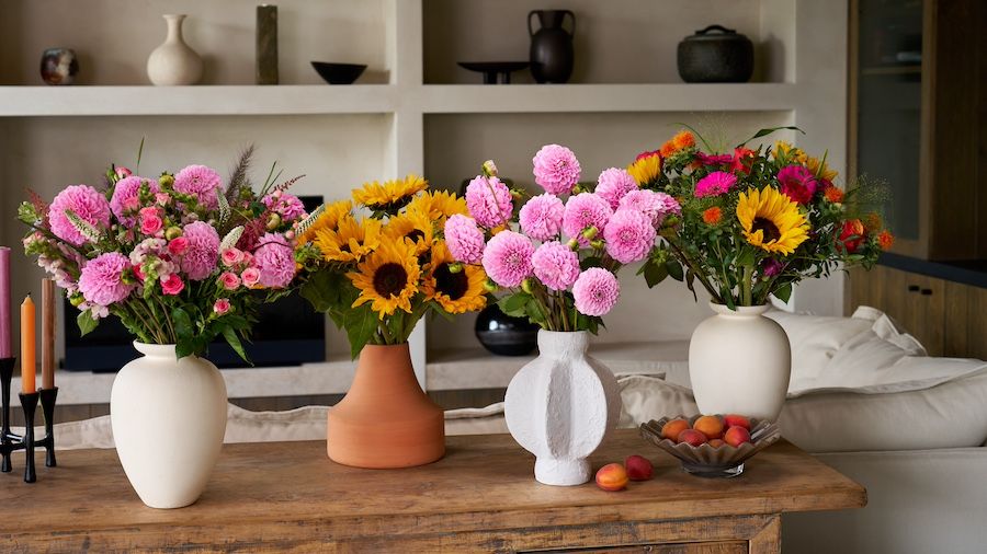 Four bouquets of sunflowers and dahlias on a sideboard in a living room