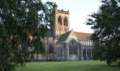 A photo of a beautiful abbey set within lush green grounds and trees.
