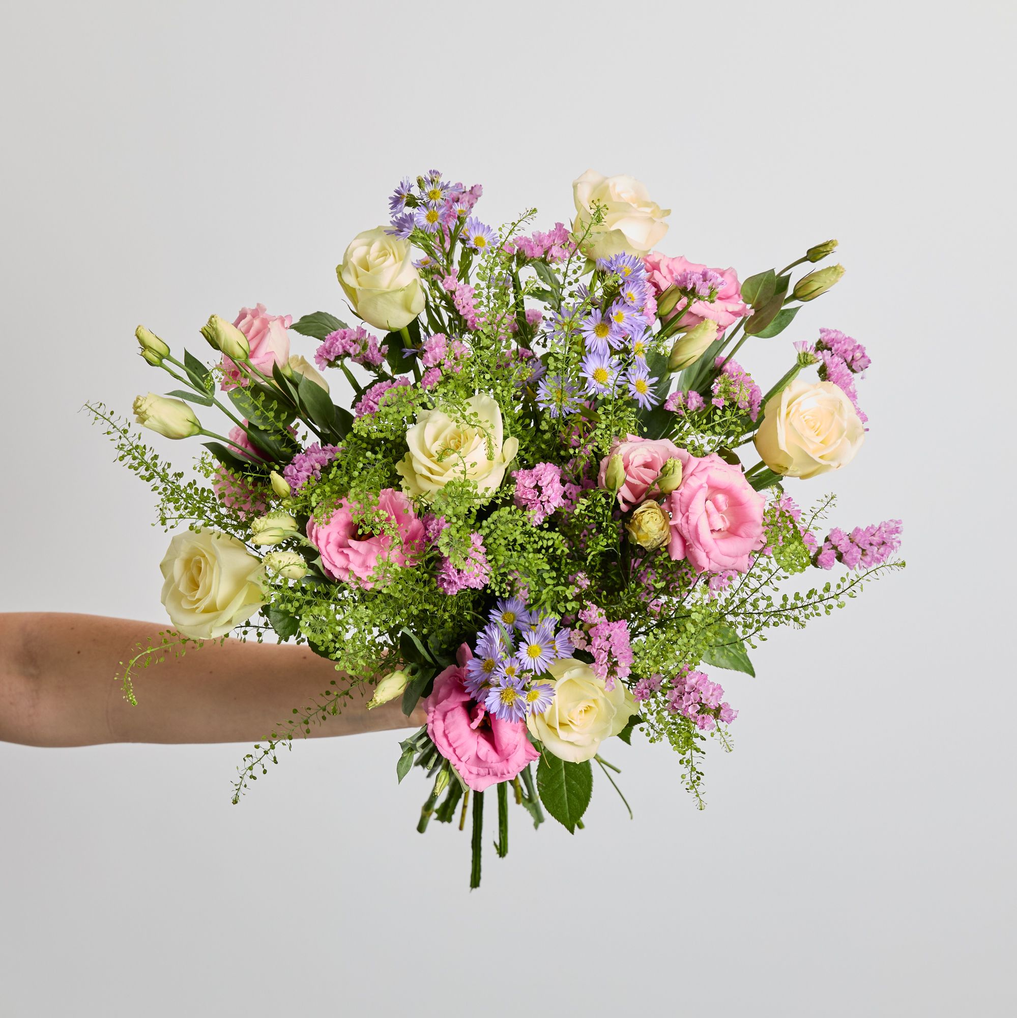 White roses, pink lisianthus, pink statice, lilac asters, and greenbell