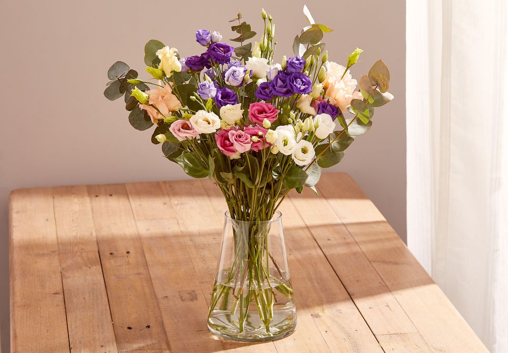 A bouquet of Lisianthus in a mix of white, pink, peach and violet, arranged with eucalyptus foliage.