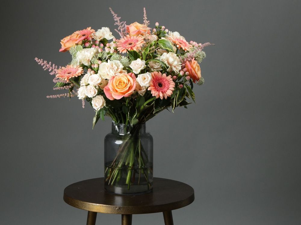 A bouquet of orange roses, coral Gerbera, white spray roses and peach hypericum.