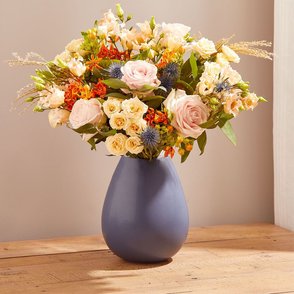 A bouquet of gorgeous peach and pink roses, thistles, orange asclepias, apricot lisianthus, eucalyptus and silvergrass